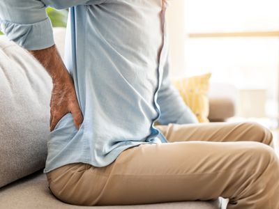 Close-up of senior man having back pain while sitting in the living room