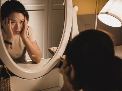 Asian woman sitting in front of the dressing table feeling depressed