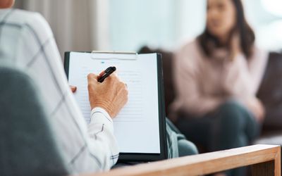 Cropped shot of a psychologist writing notes during a therapeutic session with her patient