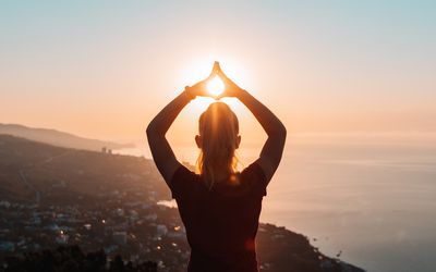 Woman at sunset with hands in air.