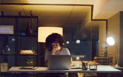 Shot of a young businesswoman looking stressed while using a laptop during a late night at work