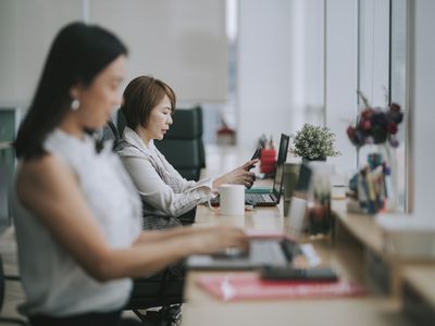 asian chinese female white collar worker working using her laptop typing in the office