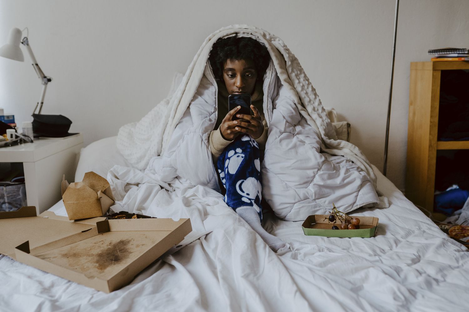 Young woman using smart phone while sitting in bedroom