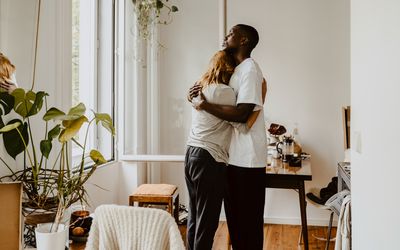 man and woman embracing while standing in living room at home