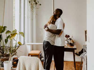 man and woman embracing while standing in living room at home