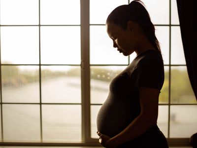 A pregnant mother thinking about her baby, tired alone at home