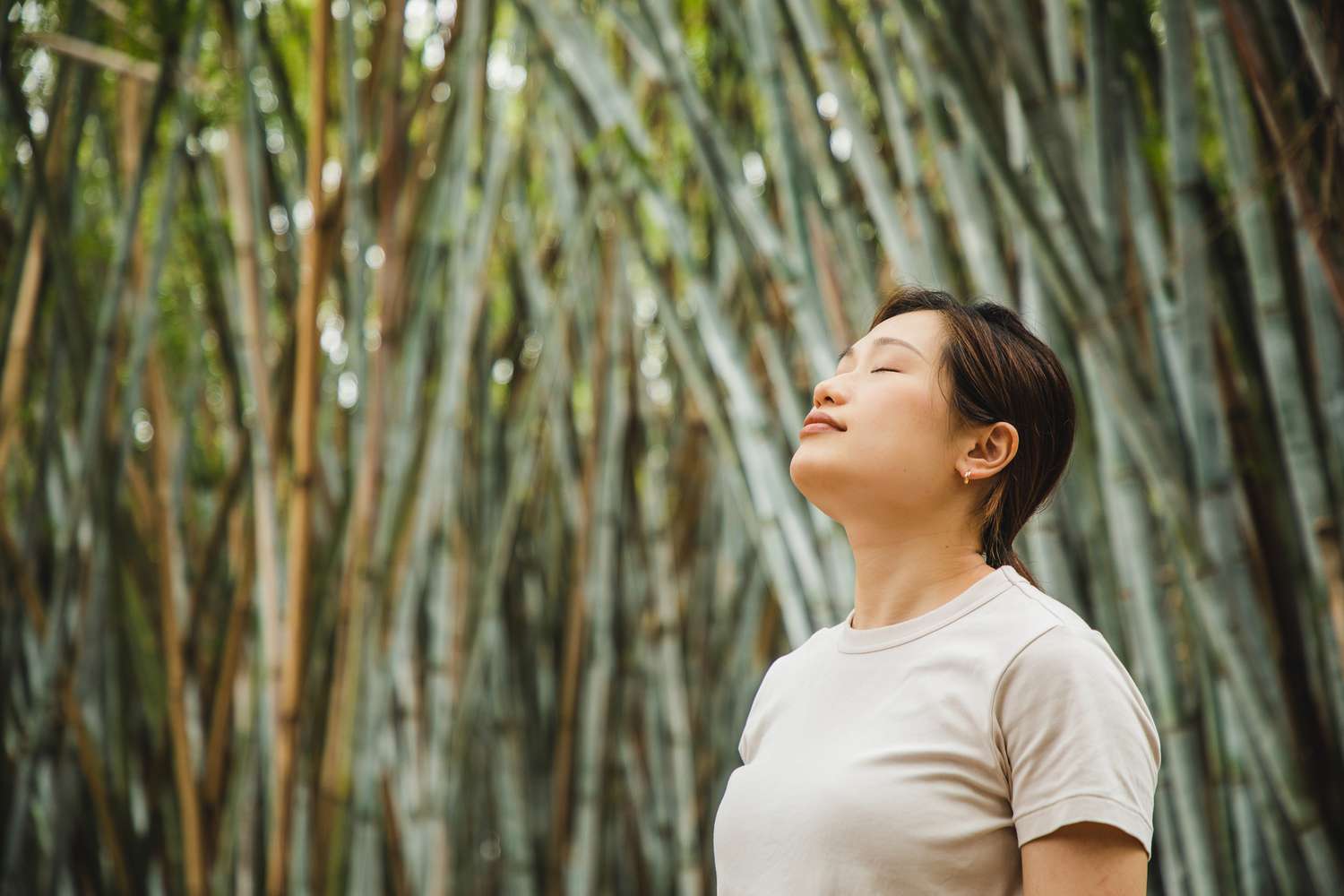 woman relaxing and breathing in fresh air in a bamboo forest