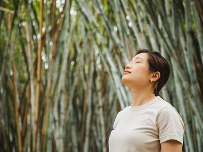 woman relaxing and breathing in fresh air in a bamboo forest