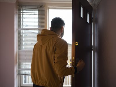 Man in yellow jacket opening door