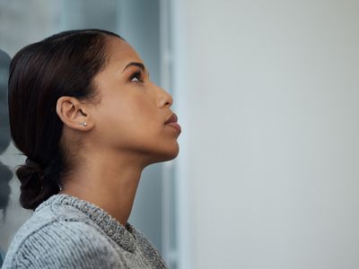 Shot of a young businesswoman taking a break and leaning against a window