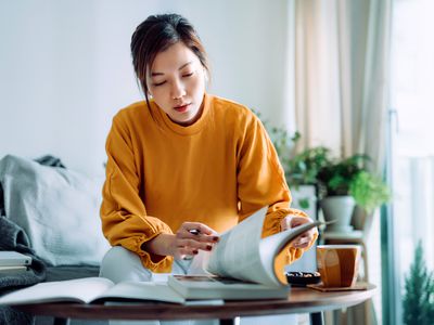 Person at a coffee table looking through a textbook