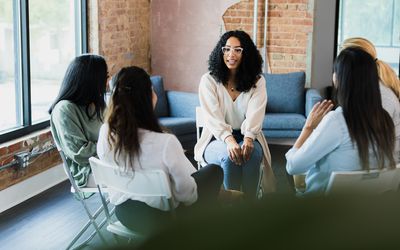 The young adult woman nervously speaks out during a meeting with her co-workers.