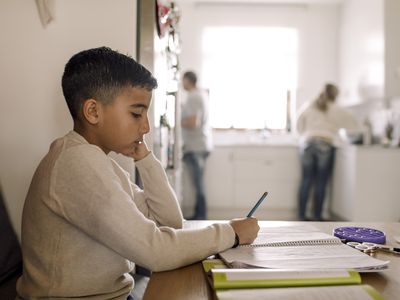 Autistic boy writing in book over table at home 