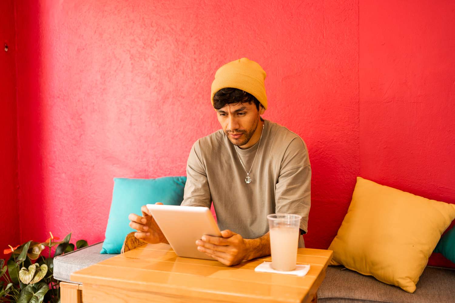 Young Latin student using digital tablet for studying . He is having a soda drink while working