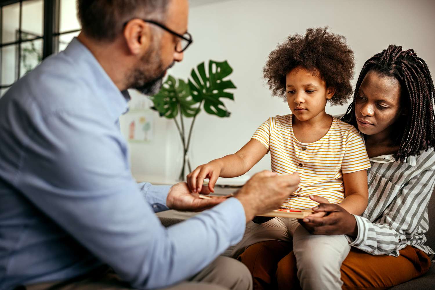 Little girl choosing toy with male psychologist