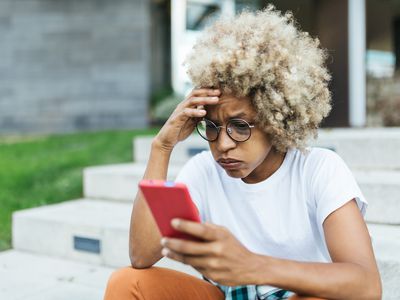 Mixed race young female looking worried and stress while reading bad news on her mobile phone. Technology concept.