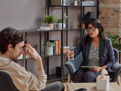 a person speaking to their therapist, while their therapist hands them a glass of water