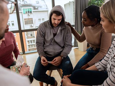 Diverse group of people sitting in circle in group therapy session.