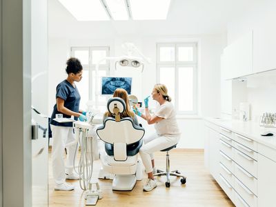 Orthodontist Showing Patient X-Ray Of Teeth In Surgery