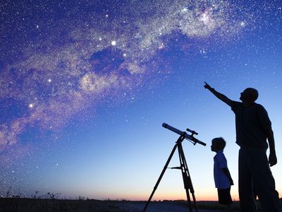 Man showing milky way to little boy, telescope