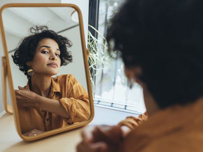 A portrait of a charming sophisticated Latin-American female taking care of her skin.