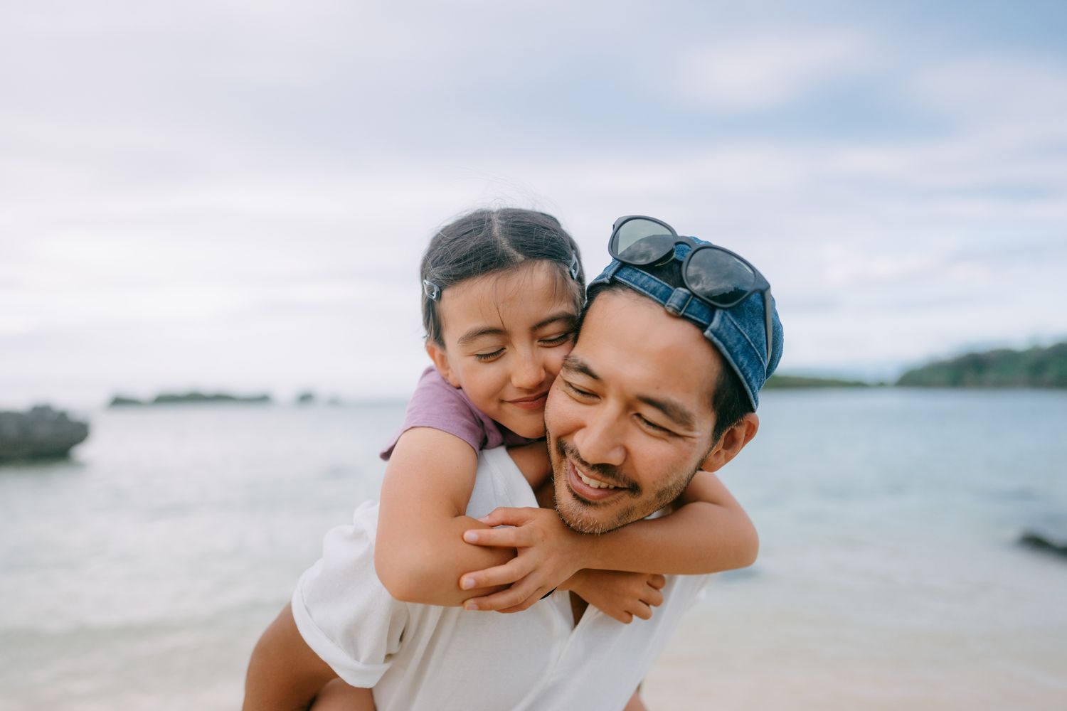 father and his young daughter having a good time on beach at dusk