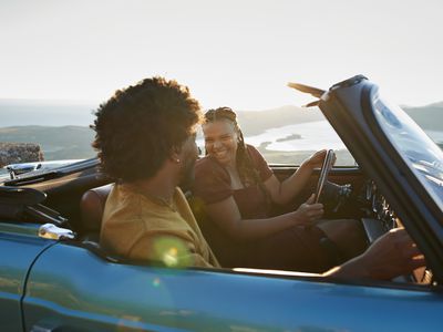 Young woman laughing while talking with boyfriend sitting in convertible car