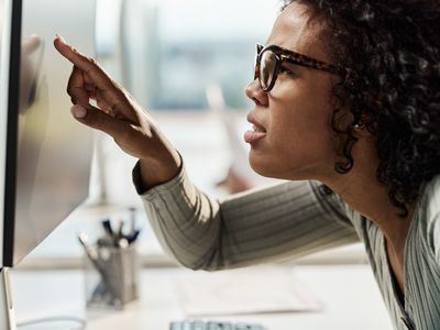 Profile view of African American female programmer with eyesight problems coding a computer language on PC in the office.