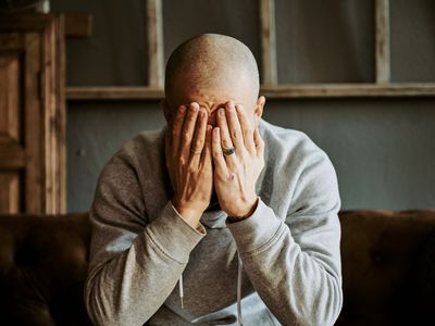 Adult man covering his face with both hands