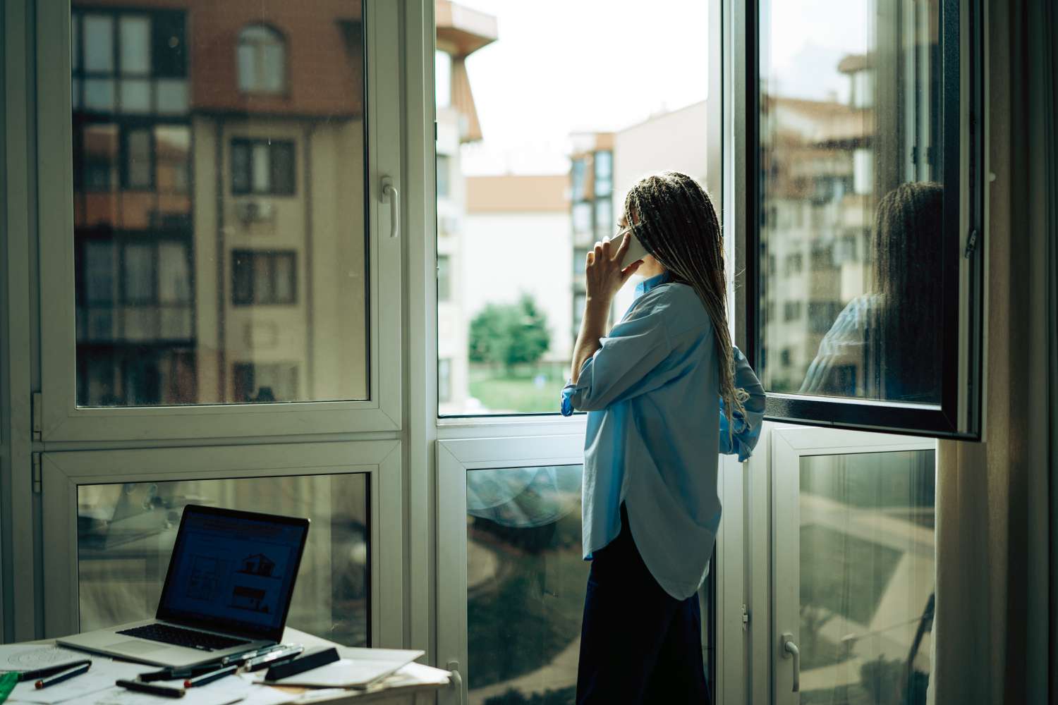 woman standing at the window and talking on the phone