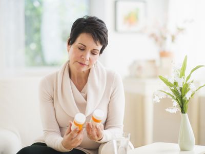 mature woman looking at pill bottles