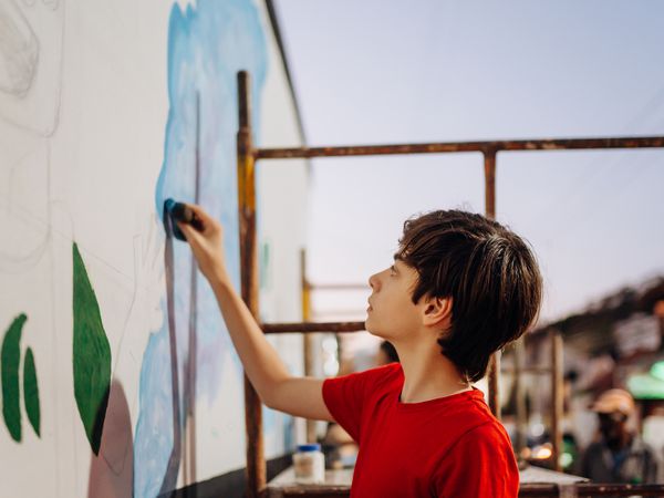 child doing an artistic wall painting in a city