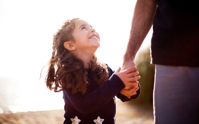 young smiling girl holding a man's hand