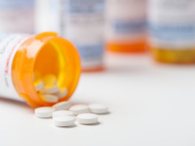 Prescription pills spill out of medication bottle on a counter.