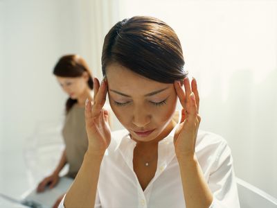 Woman with fingers pressed on temples, eyes closed