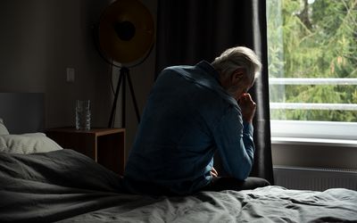 depressed senior man in bedroom