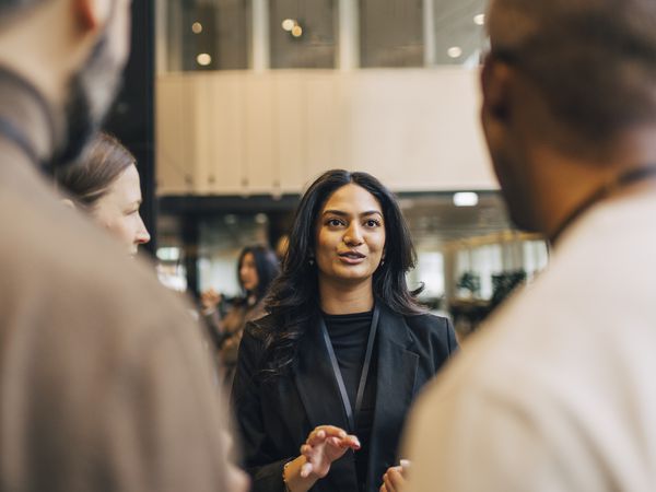 Young female entrepreneur discussing with delegates during networking event at convention center