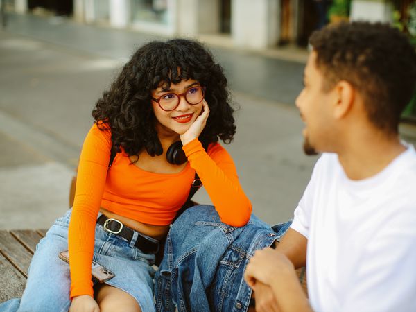 Young people having a nice time in Barcelona together, exploring the vibrant neighbourhood of Poblenou, relaxing at the bench in one of the small streets.