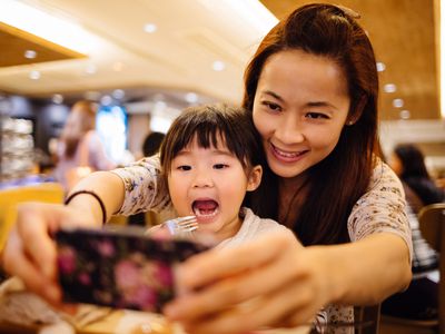 Mom & toddler girl taking selfie joyfully in cafe