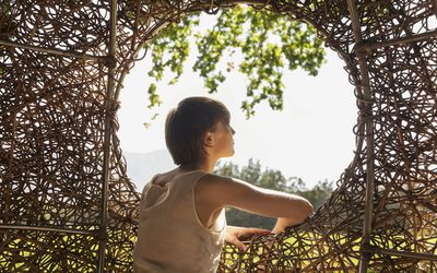 Woman looking out window of nest tree house 