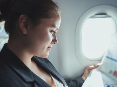 Business woman reading news in plane.