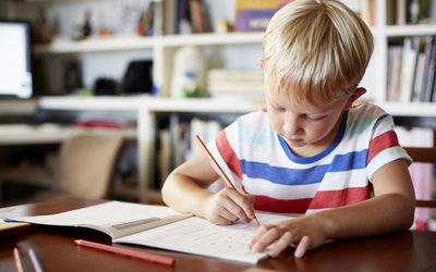 Young boy writing in workbook