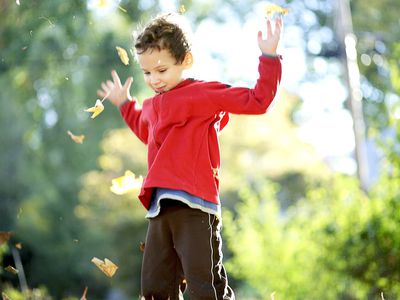 Child tossing autumn leaves into the air