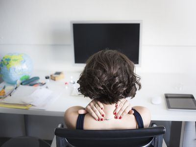 Young woman massaging her neck at desk