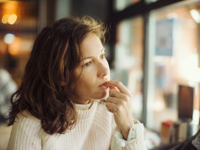 Beautiful thoughtful lady in bar, with finger in mouth.