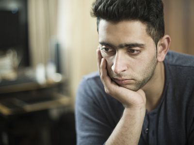 Indoor, serene young man resting head on hand and thinking