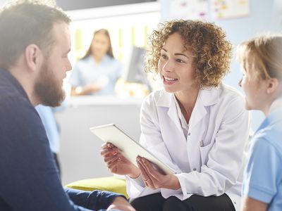 woman doctor with curly hair talking to male patient