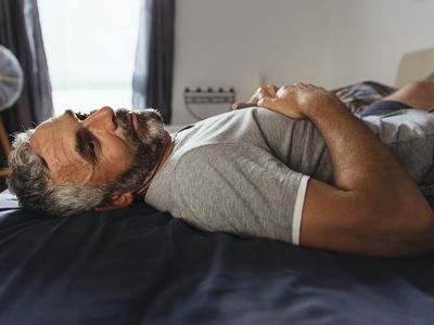 Pensive man lying on his bed at daytime