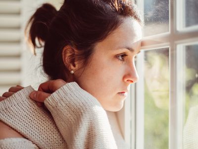 Depressed woman looking through window