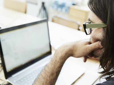 man using a laptop with his hand on his chin